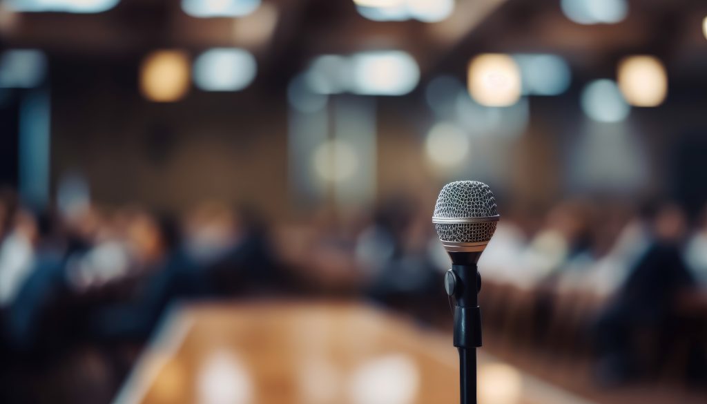 RAPPEL CE SOIR : 📢 Assemblée d’information virtuelle sur l’entente de principe Vecteezy Microphone Over The Abstract Blurred Photo Of Conference 22460921 1024x585
